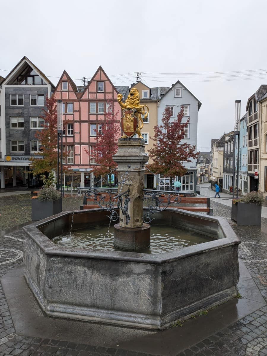 Auf dem Alten Markt in Hachenburg steht ein Brunnen mit goldenem Löwen vor bunten Fachwerkhäusern.